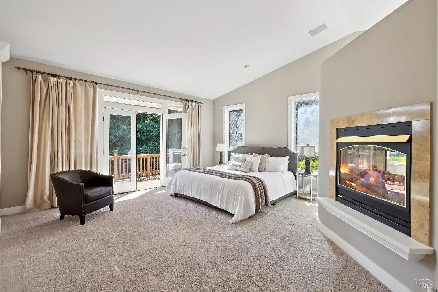 Primary bedroom with fireplace and doors to the deck